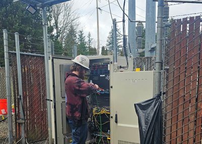 An electrician working in an electrical panel below a cell tower.