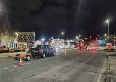 Traffic control signage and cones on a road at night.